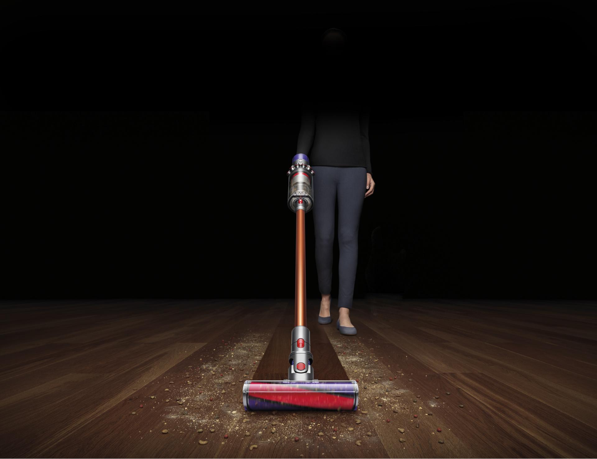 אישה באמצעות דייסון ציקלון V10 חוט ללא ואקום לאסוף פסולת מהקומה קשה