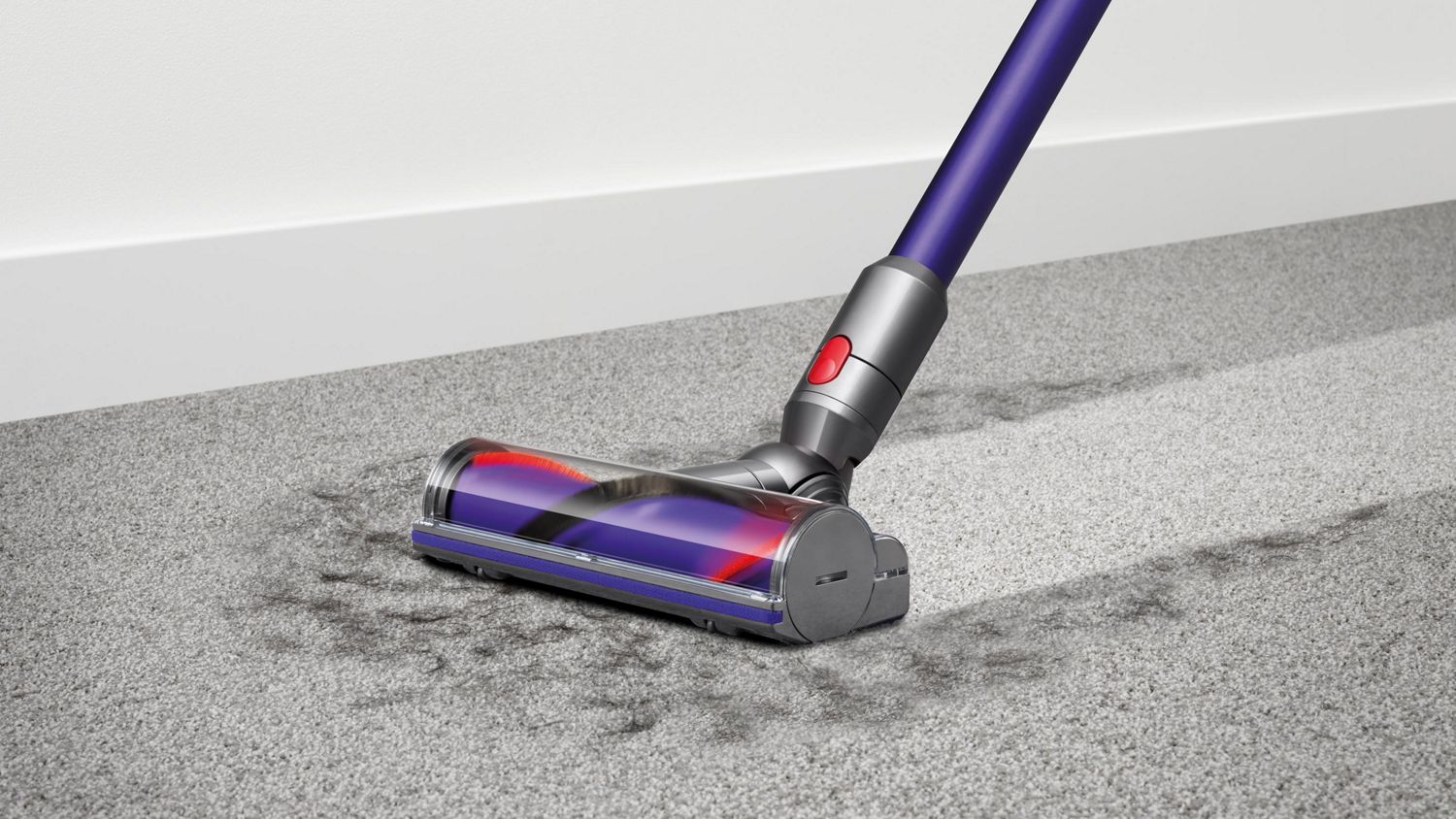 L'aspirateur sans fil Dyson V10 Animal ramasse les débris du tapis.