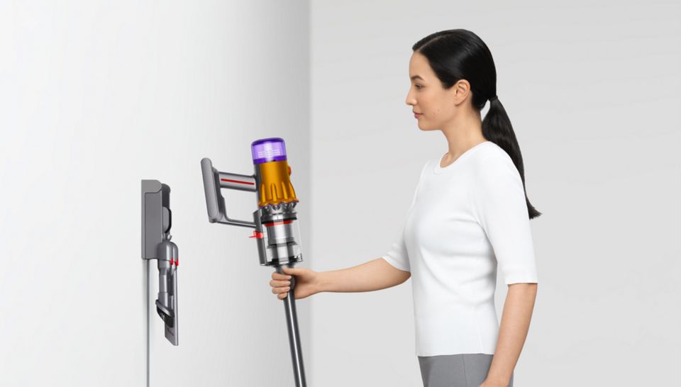 Woman placing the Dyson V12 Detect Slim vacuum on the wall dock