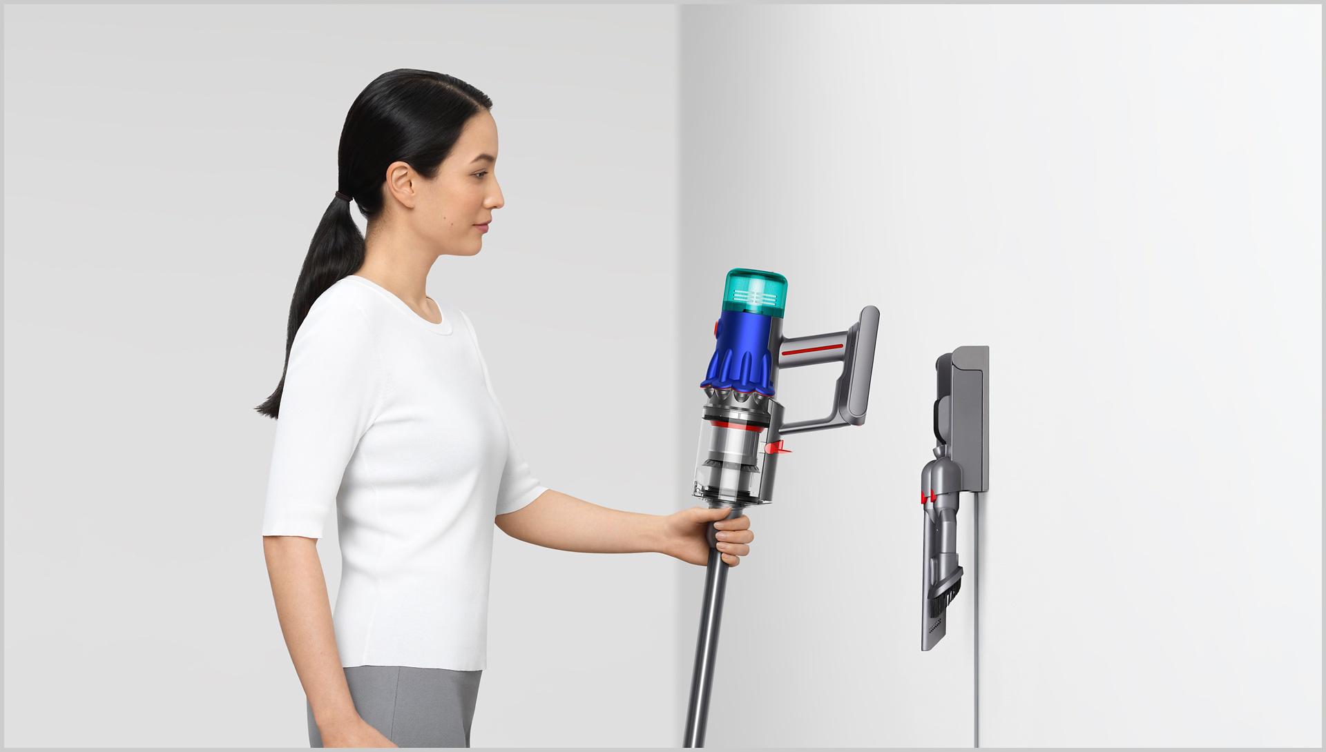 Woman placing Dyson vacuum into the wall dock