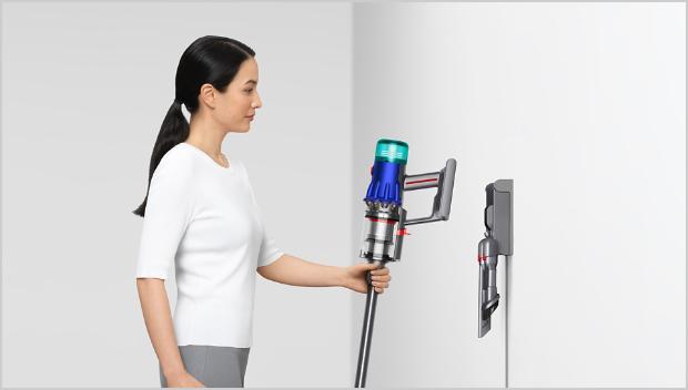 Woman placing Dyson vacuum into the wall dock