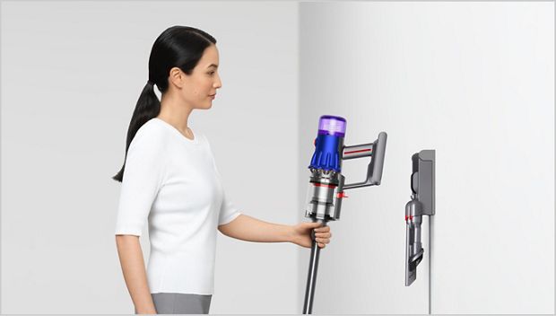 Woman placing Dyson vacuum into the wall dock