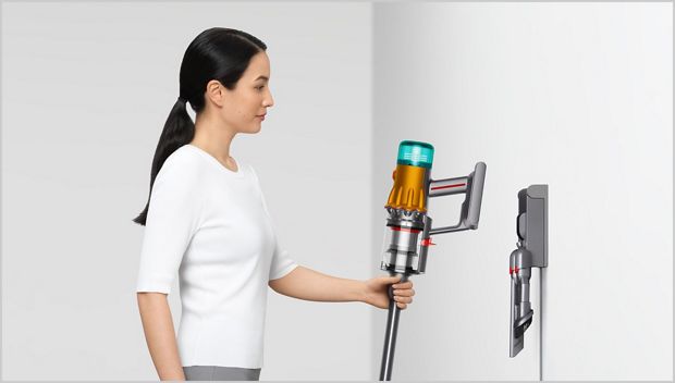 Woman placing Dyson vacuum into the wall dock