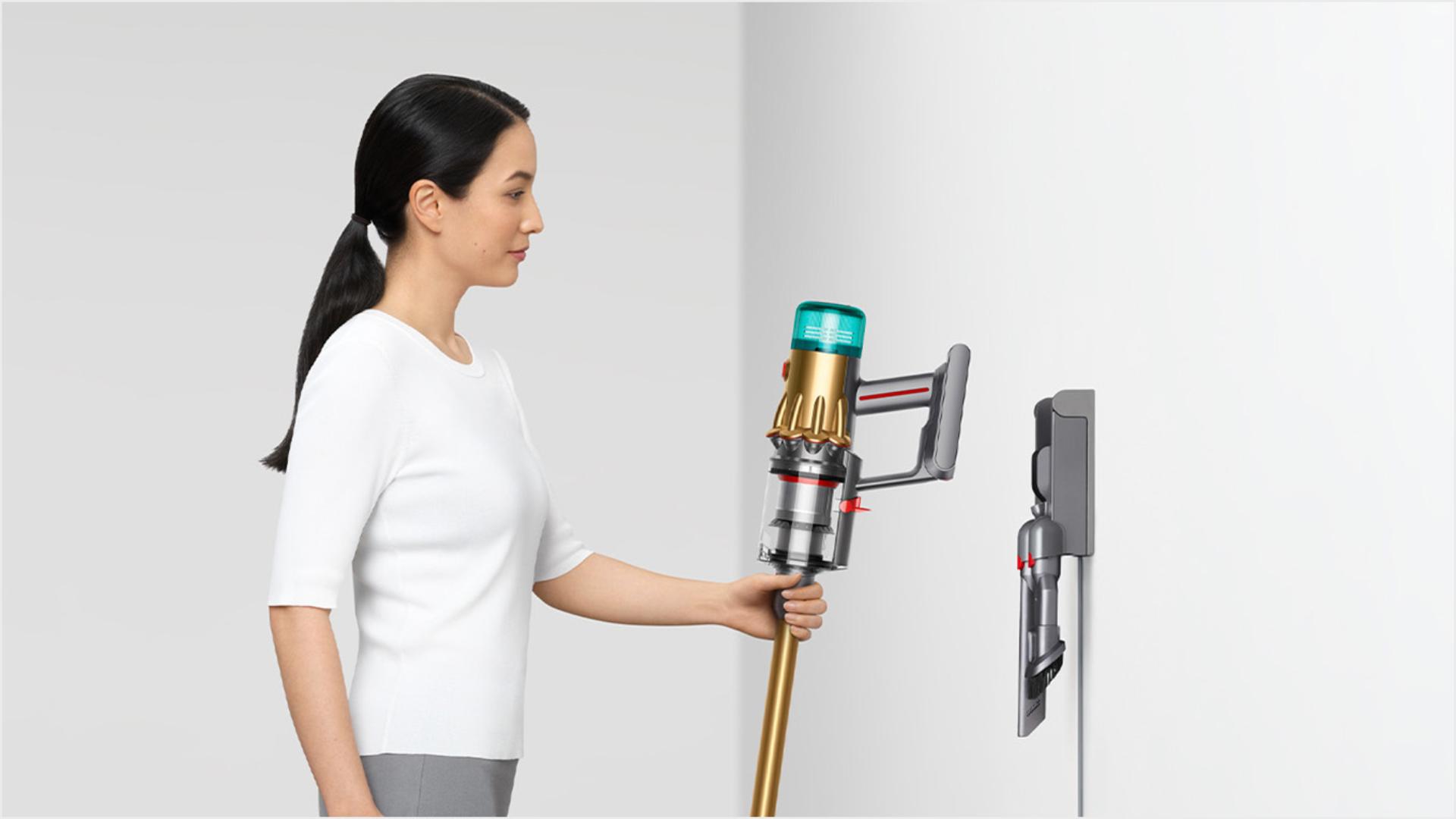 Woman dropping the vacuum into the wall-mounted charging dock.