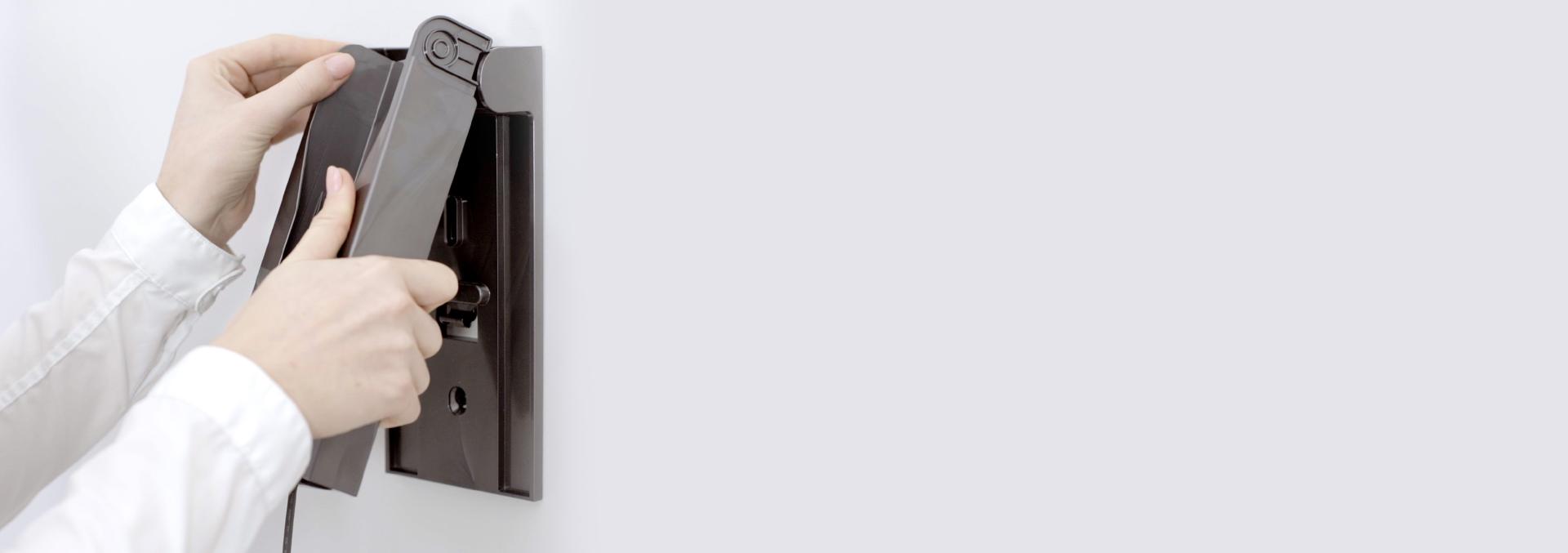 벽면 고정 장치에 충전 거치대를 끼우는 사용자의 손.