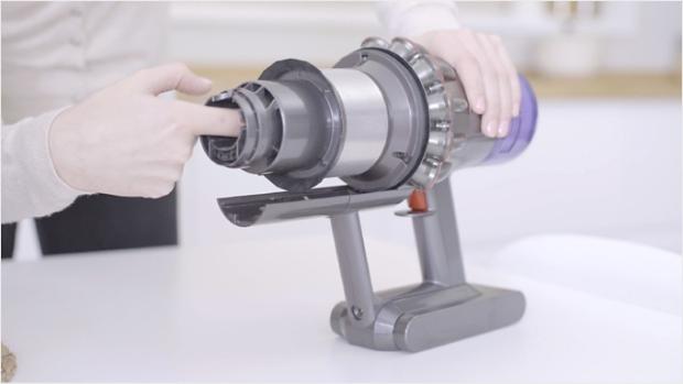 A user clearing a blockage from a dismantled machine.