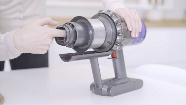 A user clearing a blockage from a dismantled machine.