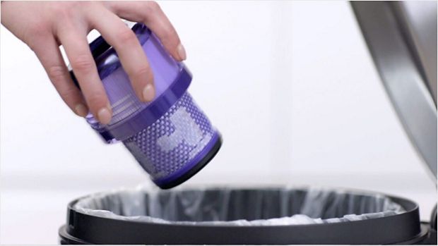 User tapping the filter to remove loose dust and debris.