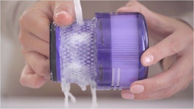 User washing the filter under a tap.