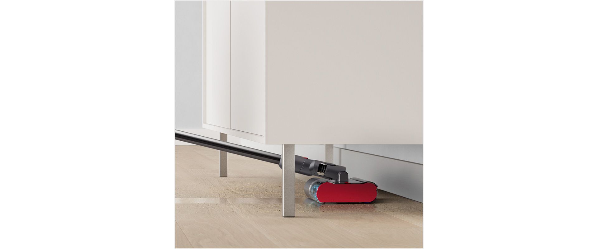Dyson Submarine™ 洗地滾筒吸頭在清潔硬地板時，深入桌子下方。