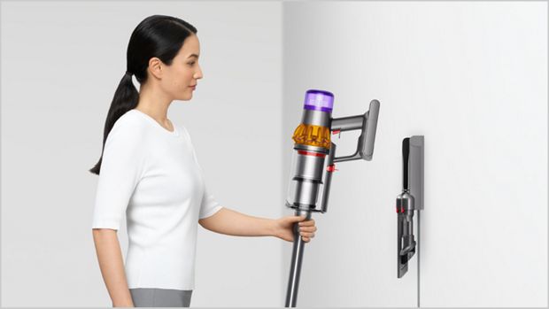 Woman placing Dyson vacuum into the wall dock