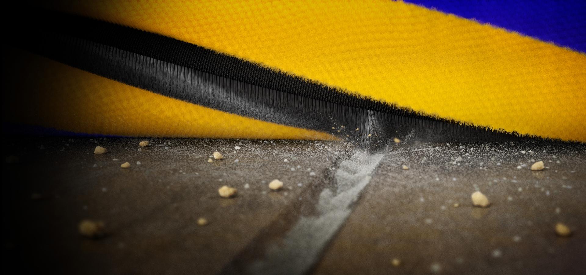 Extreme closeup of the brush bar as it rotates and the carbon fibre filament scoops up dust from a groove on a hard floor.