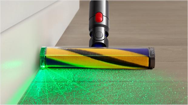 Tīrot ar putekļu sūcēju lamināta grīdu, no Fluffy Optic tīrīšanas uzgaļa izstaro zaļa gaisma.