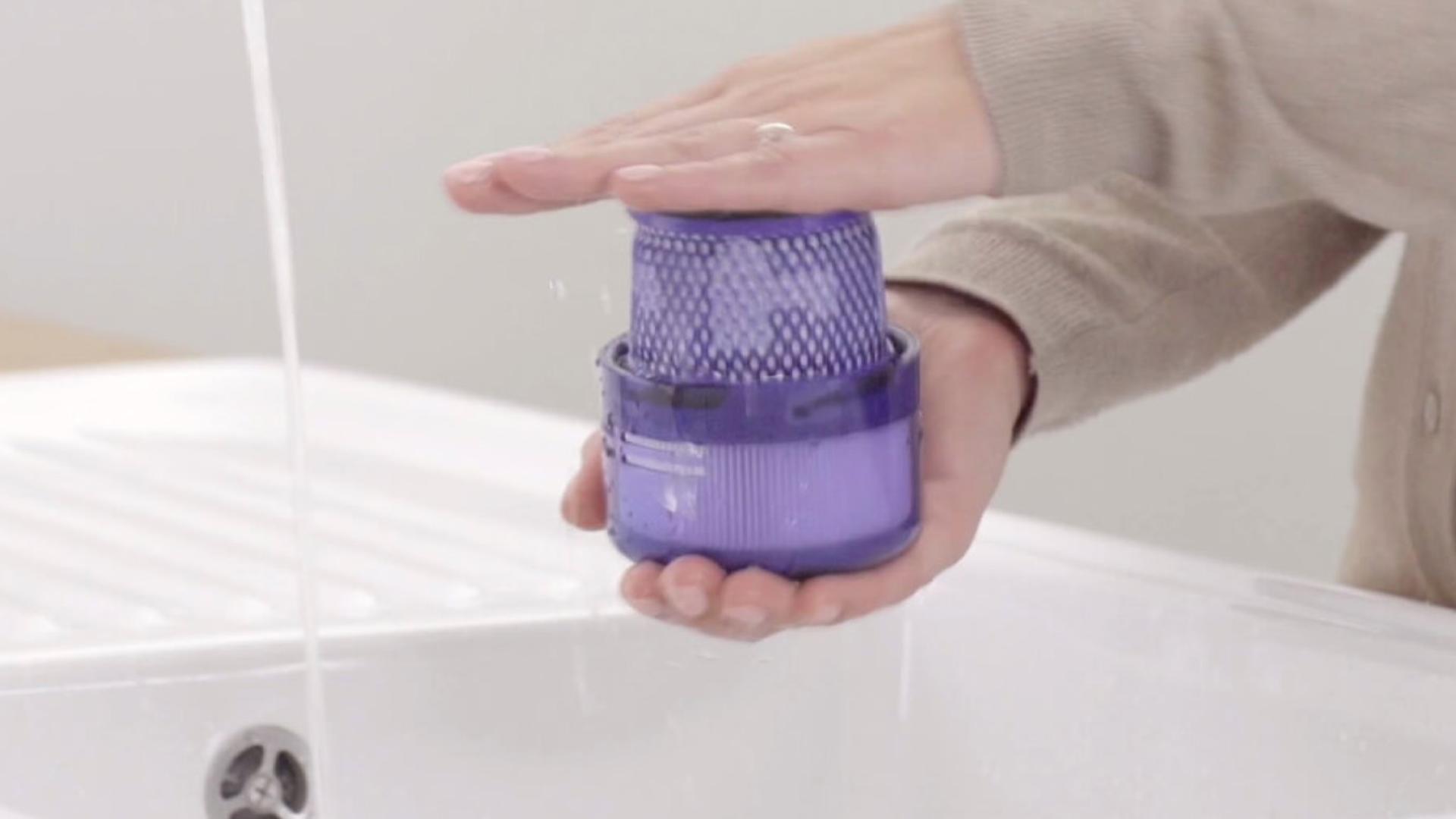 Użytkownik w trakcie mycia filtra pod wodą.