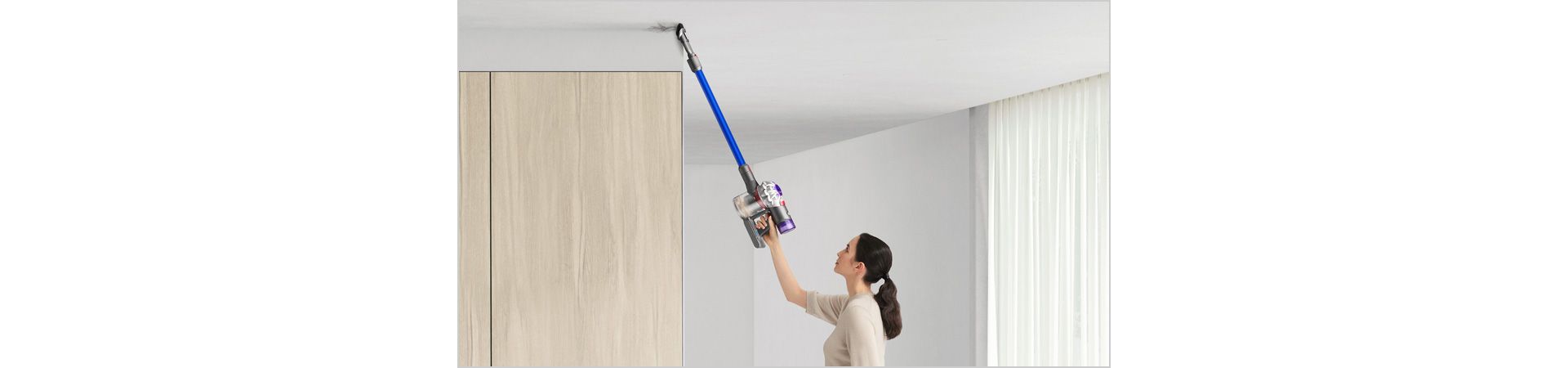 Woman cleaning up high with Dyson V7 Advanced vacuum