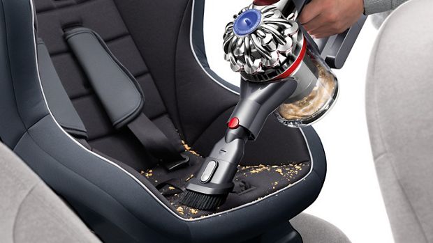 Man using handheld vacuum cleaner to clean car