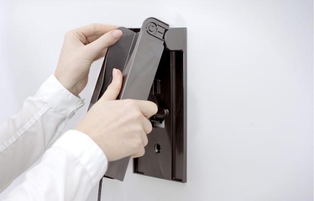 User's hands attaching dock to the wall fitting.