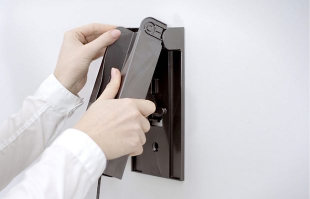 벽면 고정 장치에 충전 거치대를 끼우는 사용자의 손.