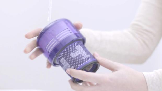 Video still of a user's hands washing the filter under a tap.