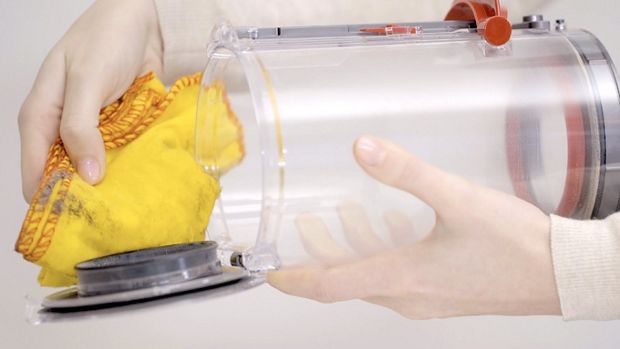 청소기의 먼지통을 청소하는 사용자.