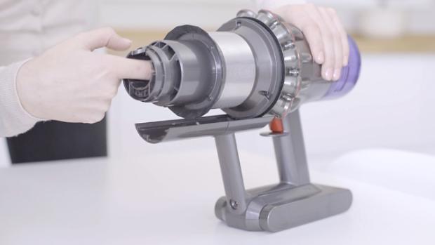 A user clearing a blockage from a dismantled machine.