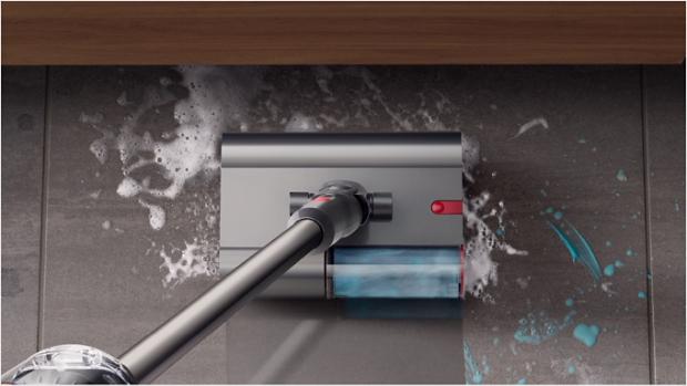 Dyson V12s Origin Submarine™ 洗地滾筒吸頭正清理浴室瓷磚地板上的肥皂水和牙膏,而前方有一個水盆。