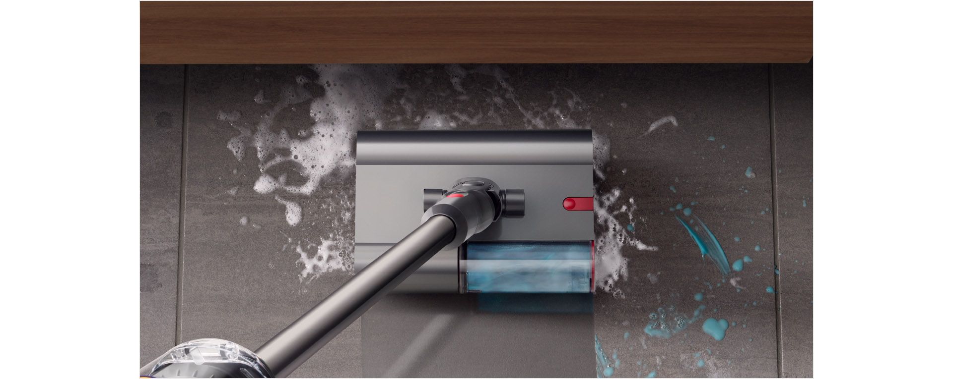 Dyson V12s Origin Submarine™ 洗地滾筒吸頭正清理浴室瓷磚地板上的肥皂水和牙膏，而前方有一個水盆。