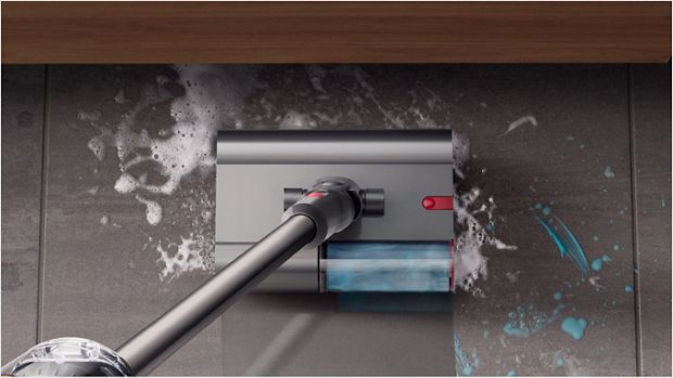 Dyson V12s Origin Submarine™ 洗地滾筒吸頭正清理浴室瓷磚地板上的肥皂水和牙膏，而前方有一個水盆。