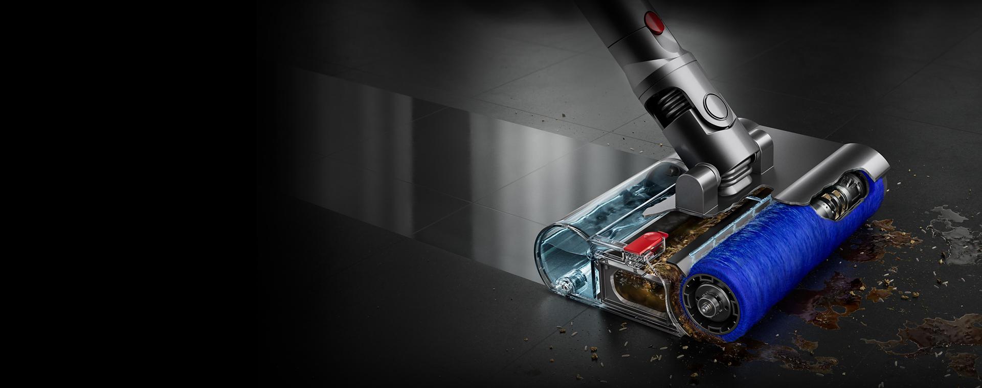 Cutaway closeup of the motorised wet roller on a stone floor with some debris to the front and side leaving behind a clean sheen.