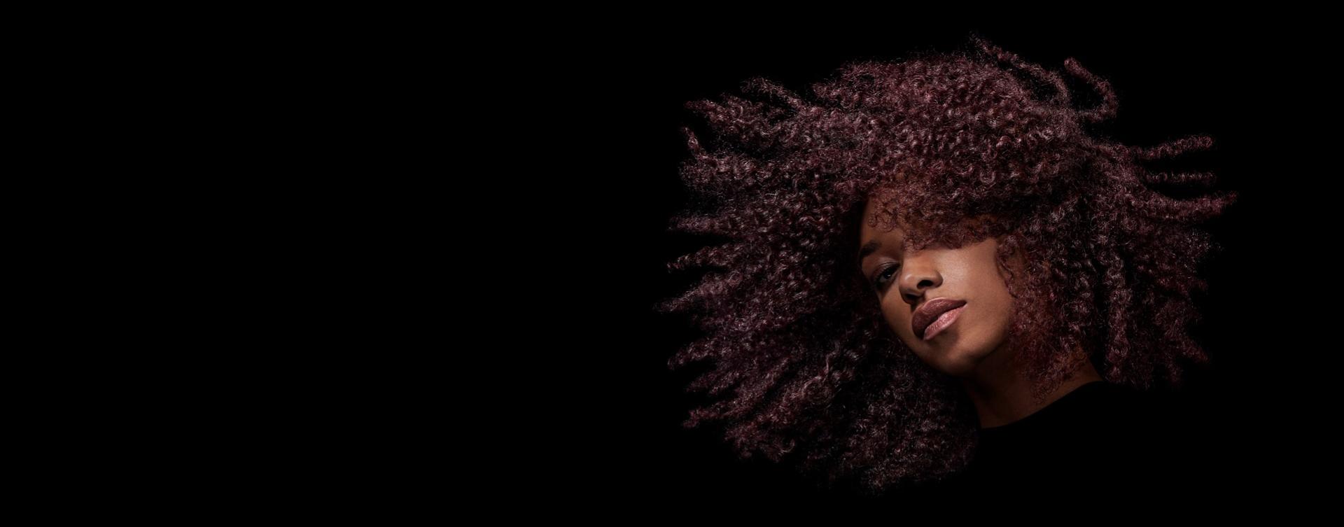 곱슬머리 모델이 스타일링한 머리를 흔들고 있다.