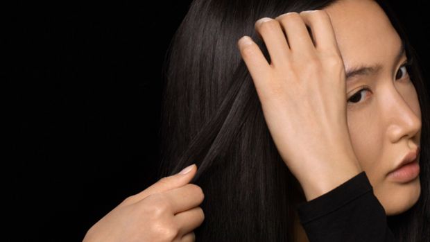 Model smooths product through her damp hair.