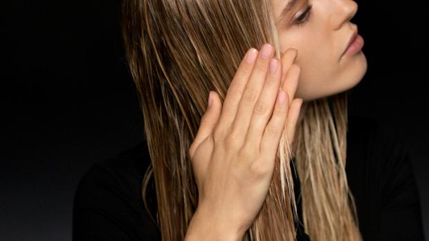 Model smooths product through her damp hair.