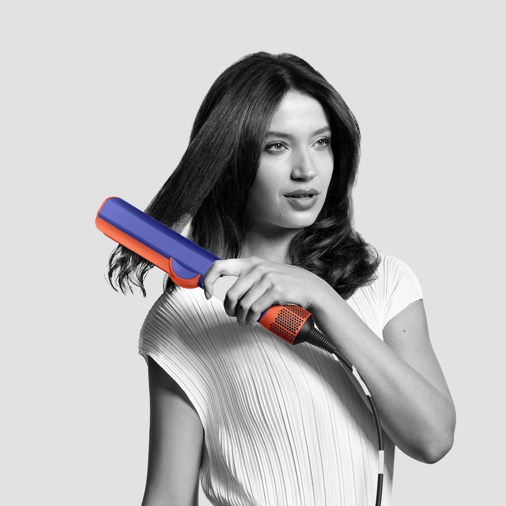 Un model folosește placa de păr Dyson Airstrait pentru a-și coafa părul.