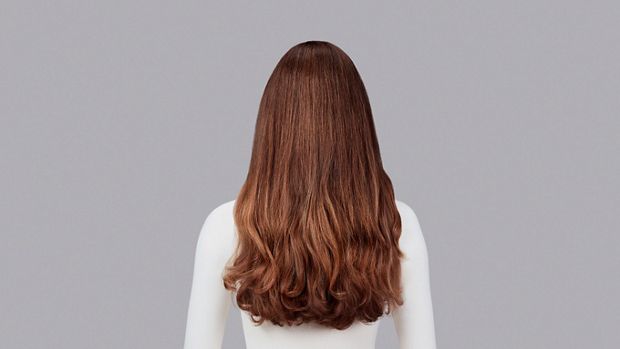Naturally curly light brown hair styled with Dyson Chitosan Pre-style cream and the Dyson Airwrap. Seen from behind.