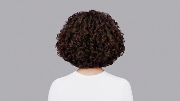 Naturally curly dark brown hair styled with Dyson Chitosan Pre-style cream and the Dyson Supersonic r. Seen from behind.