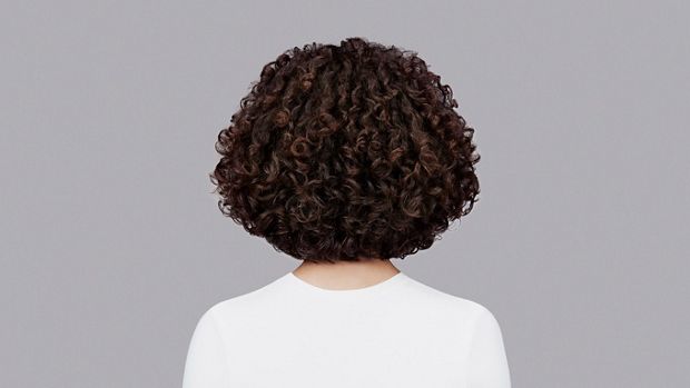 Naturally curly dark brown hair styled with Dyson Chitosan Pre-style cream and the Dyson Supersonic r. Seen from behind.