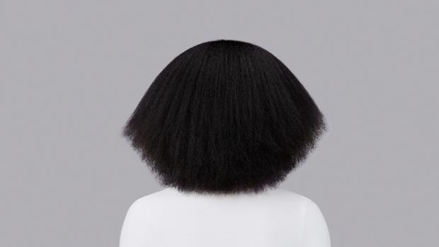 Naturally coily brown hair styled with Dyson Chitosan Pre-style cream and the Dyson Supersonic Nural. Seen from behind.