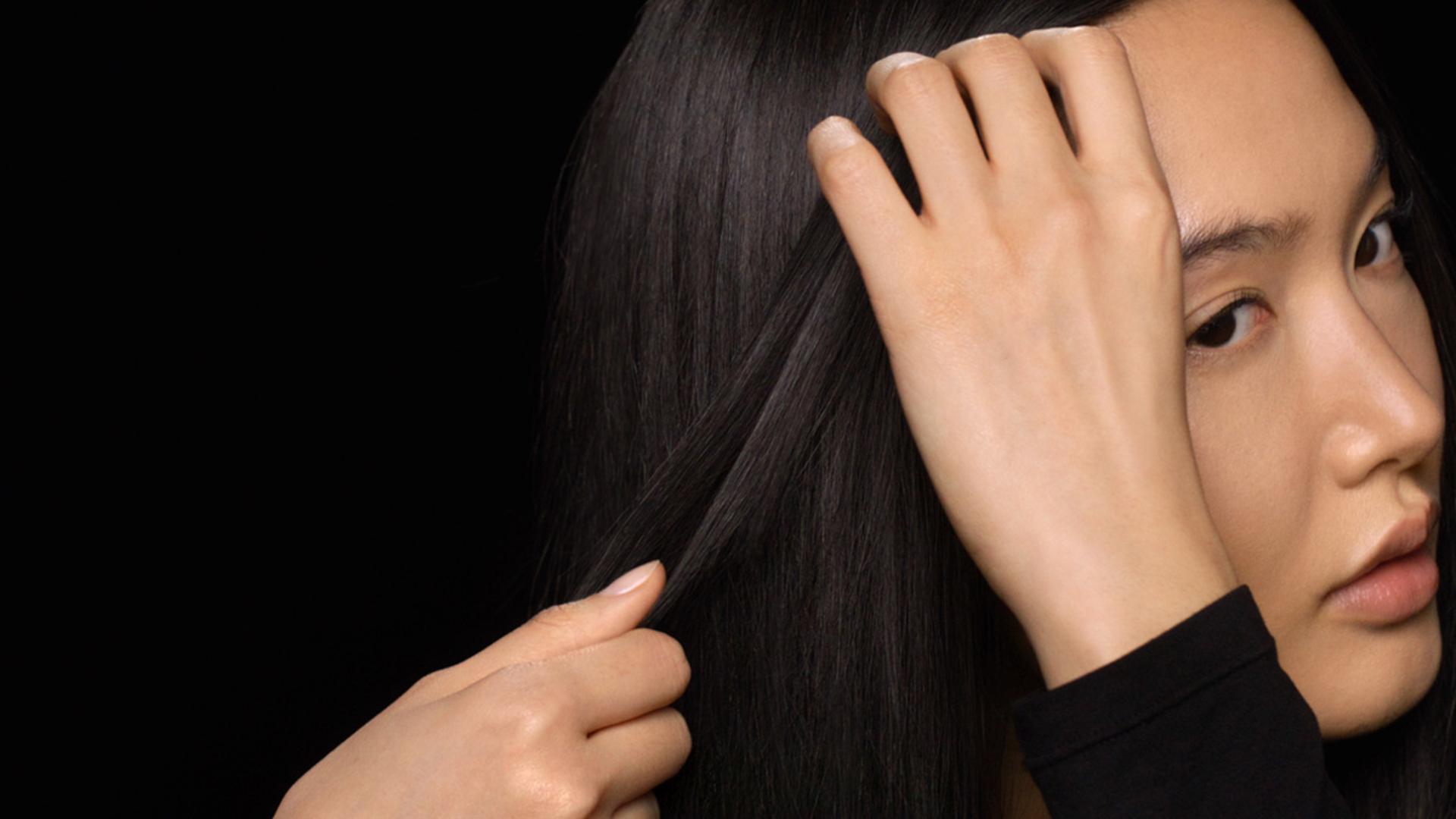 Modelka używa rąk do wygładzenia produktu na całej długości.