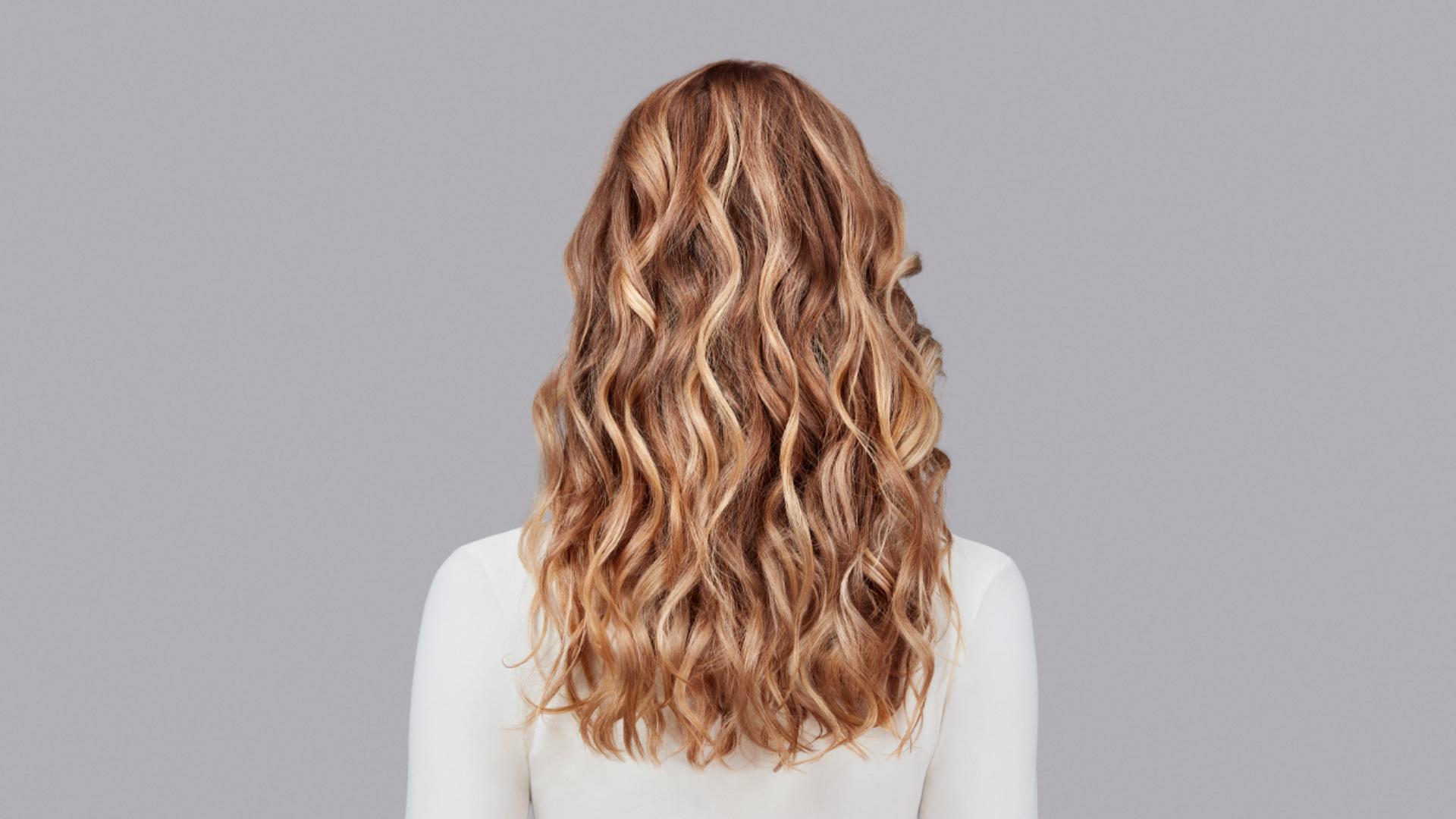 Naturally wavy blonde hair styled with Dyson Chitosan Pre-style cream and the Dyson Airwrap. Seen from behind.