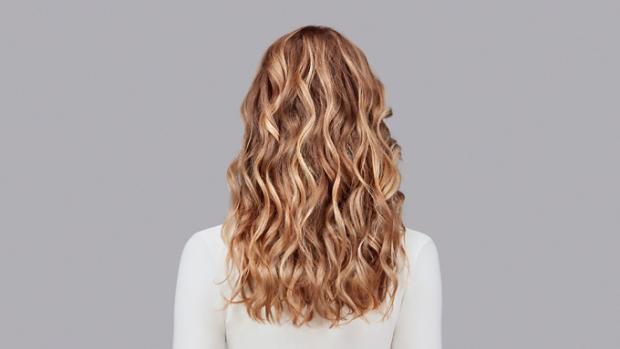 Naturally wavy blonde hair styled with Dyson Chitosan Pre-style cream and the Dyson Airwrap. Seen from behind.