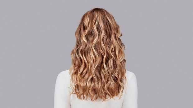 Naturally wavy blonde hair styled with Dyson Chitosan Pre-style cream and the Dyson Airwrap. Seen from behind.