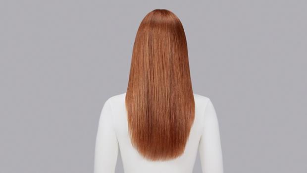 Naturally wavy auburn hair straightened with Dyson Chitosan Pre-style cream and the Dyson Supersonic Nural. Seen from behind.