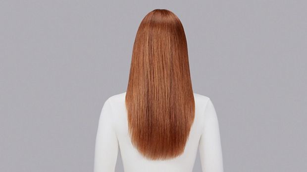 Naturally wavy auburn hair straightened with Dyson Chitosan Pre-style cream and the Dyson Supersonic Nural. Seen from behind.