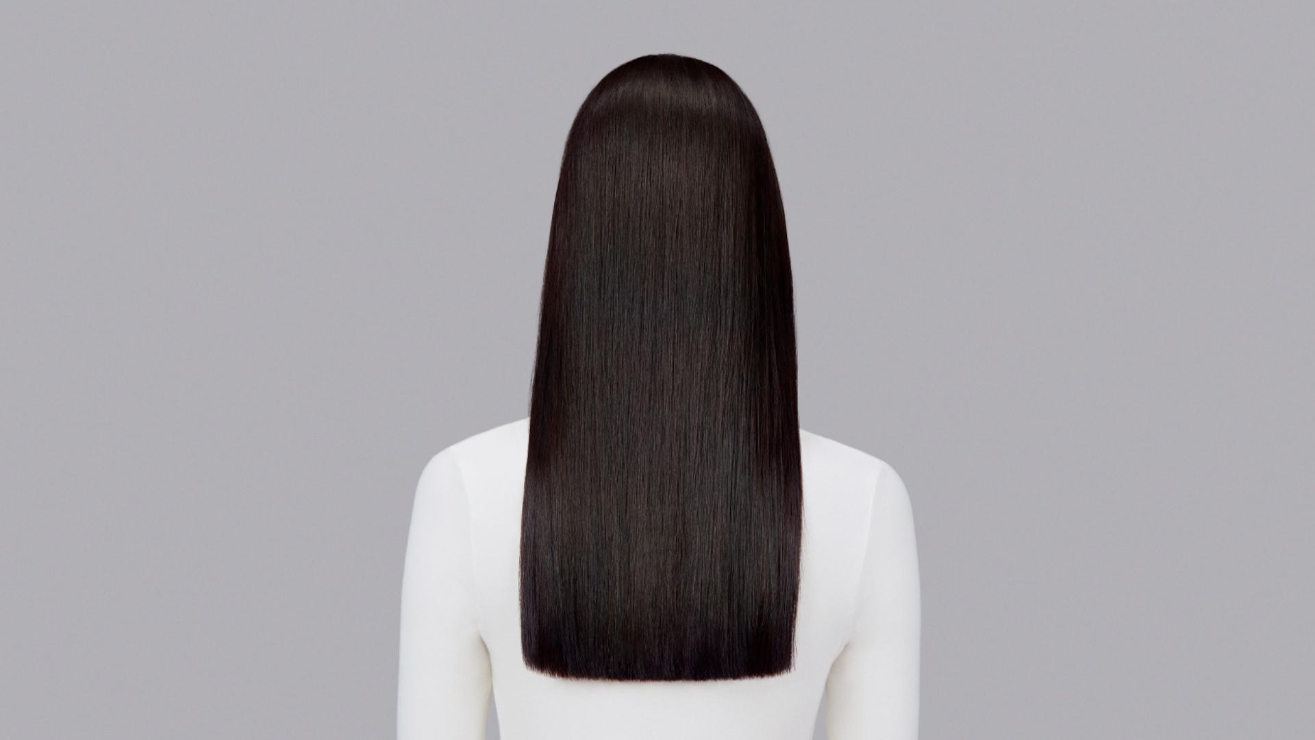 Naturally straight dark hair styled with Dyson Chitosan Pre-style cream and the Dyson Airstrait. Seen from behind.