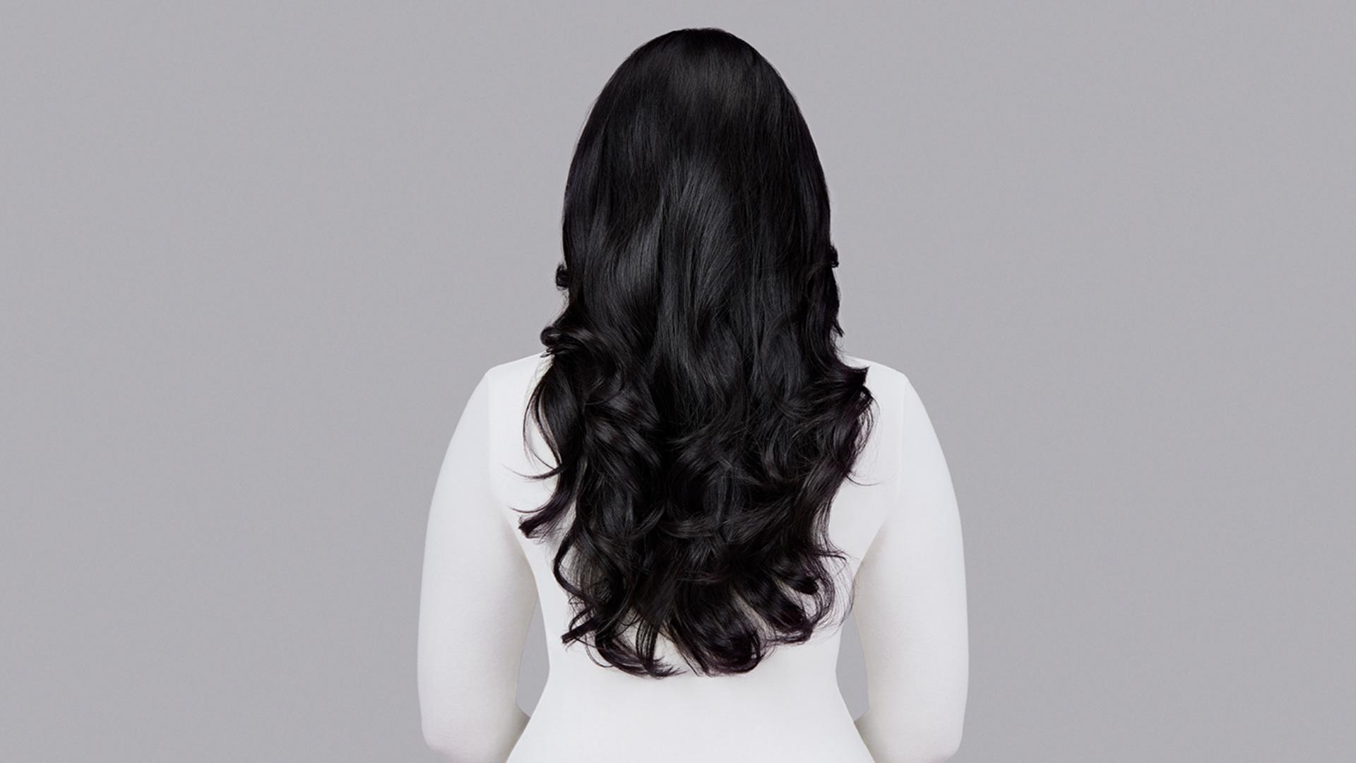 Naturally straight dark hair styled into waves with Dyson Chitosan Pre-style cream and the Dyson Airwrap. Seen from behind.