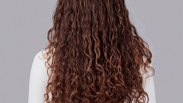 Model with long curly brown hair.