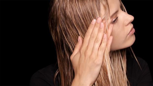 A blonde model applies Dyson Chitosan Pre-style cream to her hair with her hands.