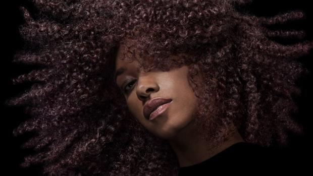 عارِضة تقوم بتحريك شعرها البني الملفوف لإبراز ثباته.