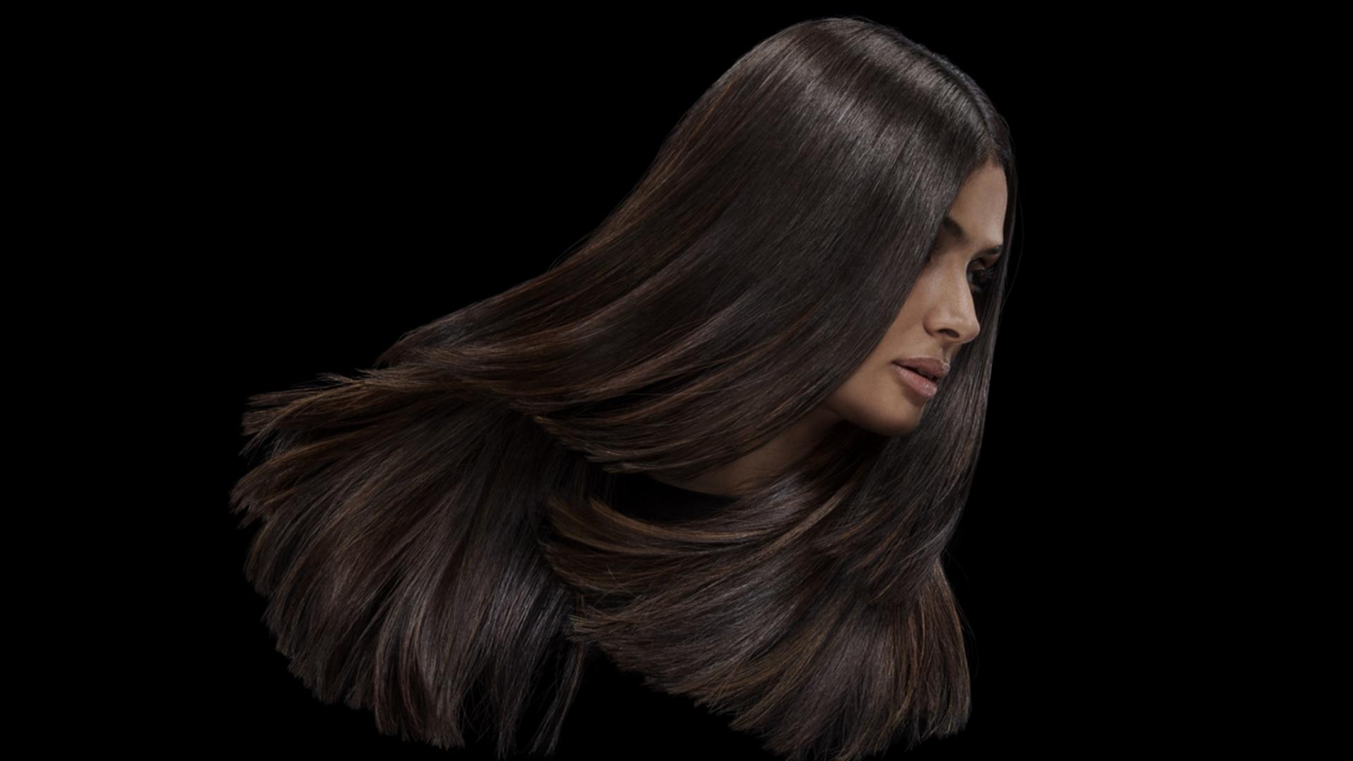 عارِضة شعرها بني طويل وكثيف ولامع.