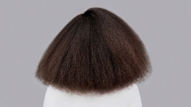 Naturally coily dark brown hair styled with Dyson Chitosan Pre-style cream and the Dyson Supersonic Nural. Seen from behind.